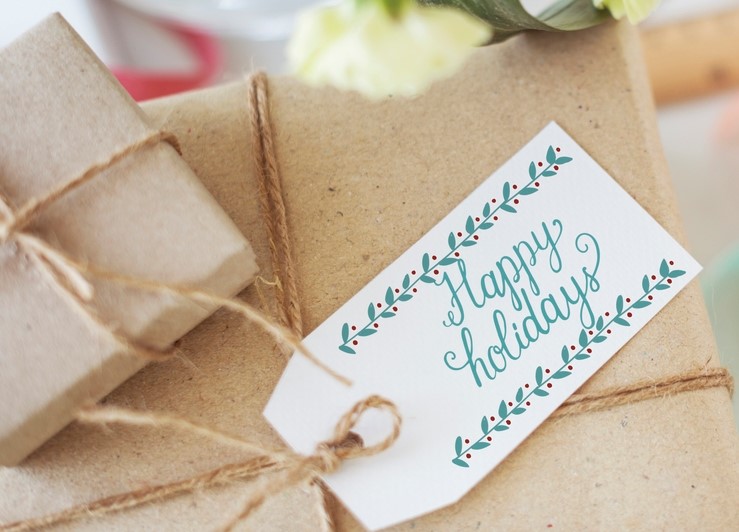 A "Happy Holidays" gift tag on a naturally wrapped gift